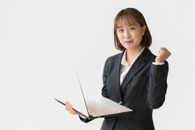スーツ姿でノートパソコンを持つ女性