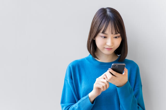 スマートフォンを操作する青い服の女性